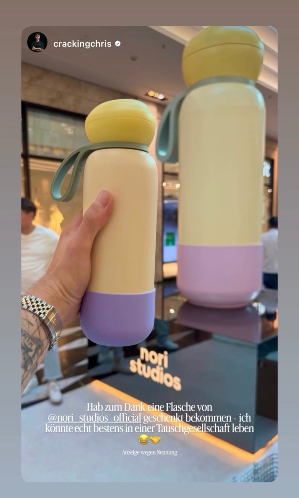 Two yellow and lilac nori bottles held up in a shopping centre