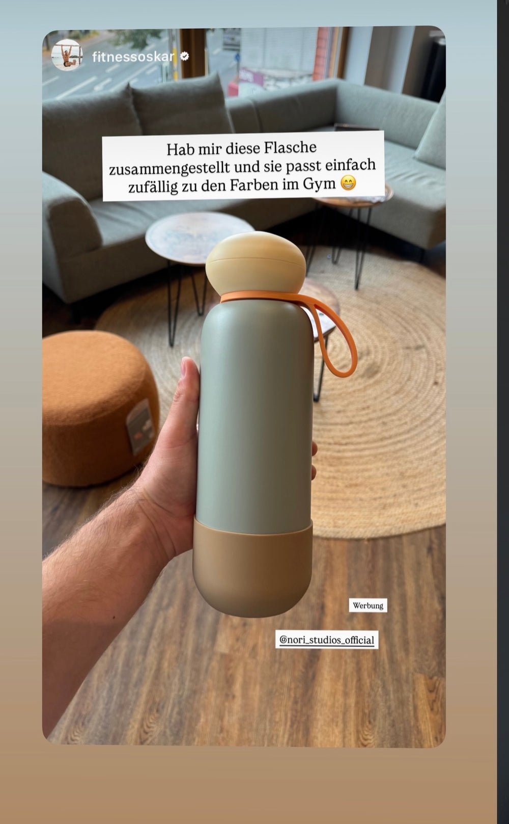 Sage and taupe nori bottle held up in a gym lounge