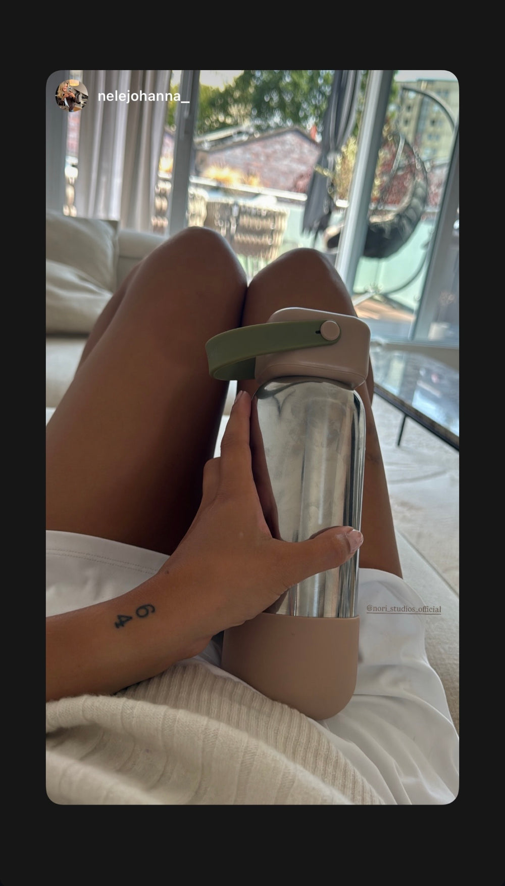 Chrome nori bottle with a sage cap, held while lounging by a pool