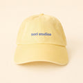 Butter yellow nori studios cap with a blue embroidered wordmark